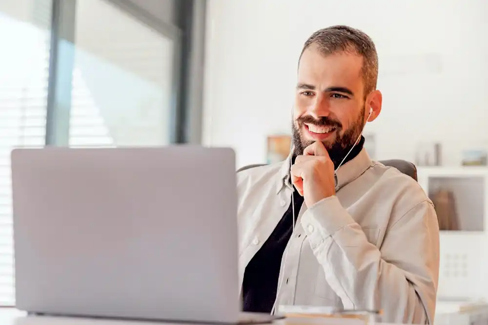 Empresário em reunião online usando notebook e fone de ouvido.