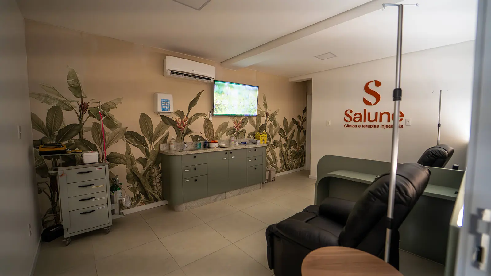 Sala de terapias injetáveis da Clínica Salune com poltronas reclináveis e logo da marca na parede.